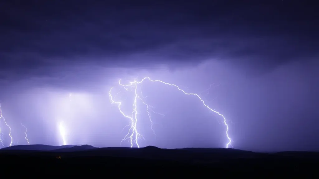 Thunderstorm over mountainous terrain, representing interference Illustration of cosmic particle showers in Earth's atmosphere