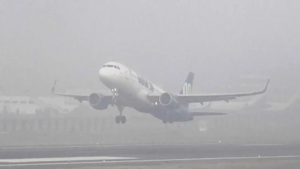 "Dense fog shrouds Delhi's IGI Airport runway" "Passengers waiting at Delhi airport amidst fog delays" "Aircraft on taxiway during low visibility at IGI Airport"